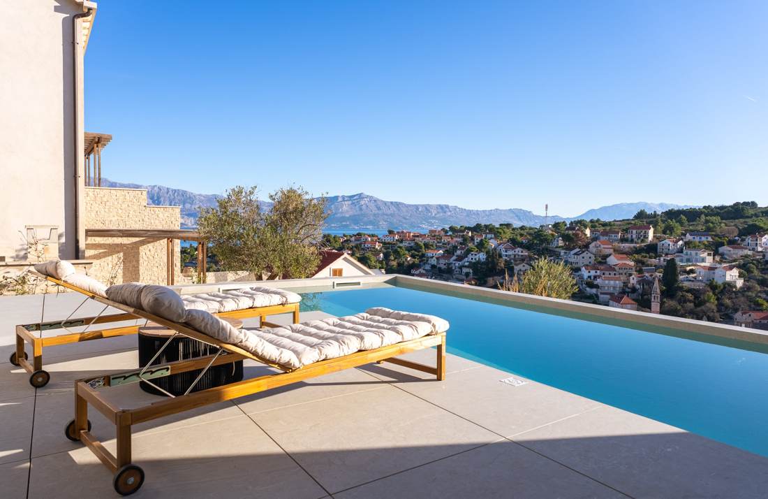 Sun loungers by the pool with sea and mountain views