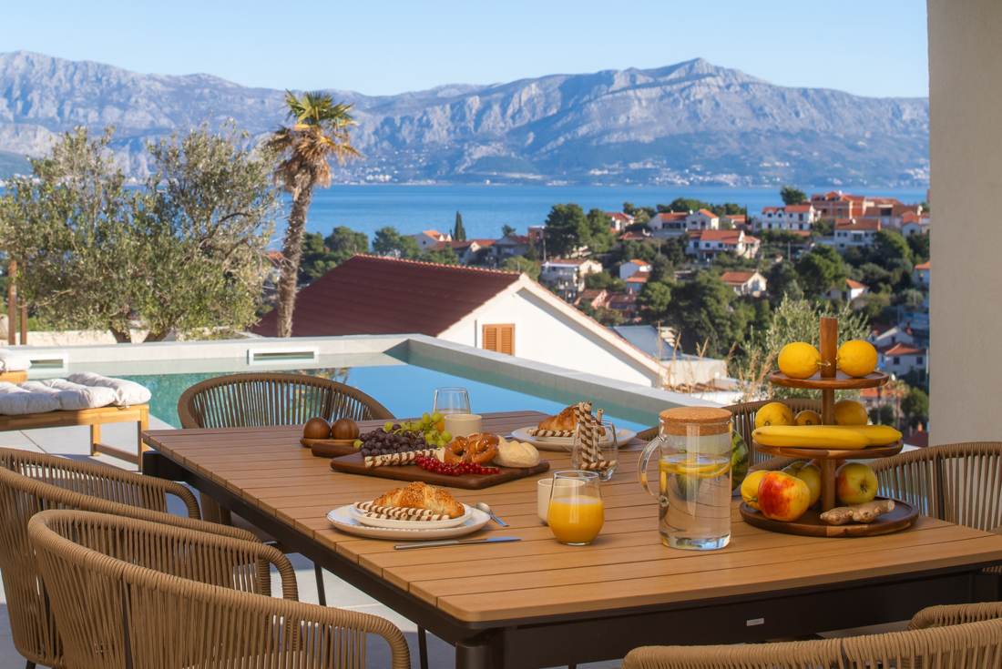 Breakfast table with the pool and sea behind it
